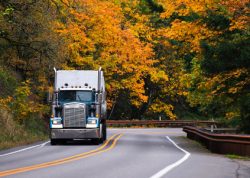 Truck driving on a country road during the fall.
